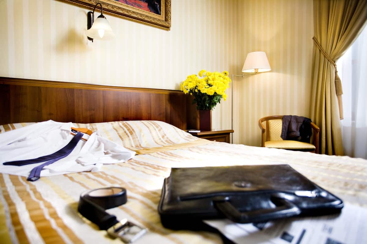 Et hotelværelse med en seng, et natbord, en stol og en lampe.