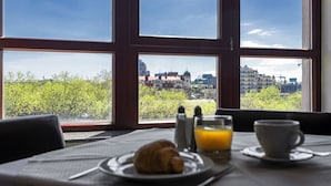 A breakfast setup with croissant, orange juice, and coffee on a table with a city view through large windows. - Ayvazovsky (Odesa)