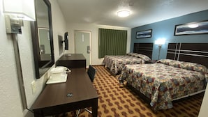 A hotel room with a desk, two beds, a mirror, a telephone, and a headboard with a light. - Lodge Inn (Wrightstown)