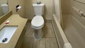 A bathroom with a toilet, sink, and shower. - Lodge Inn (Wrightstown)