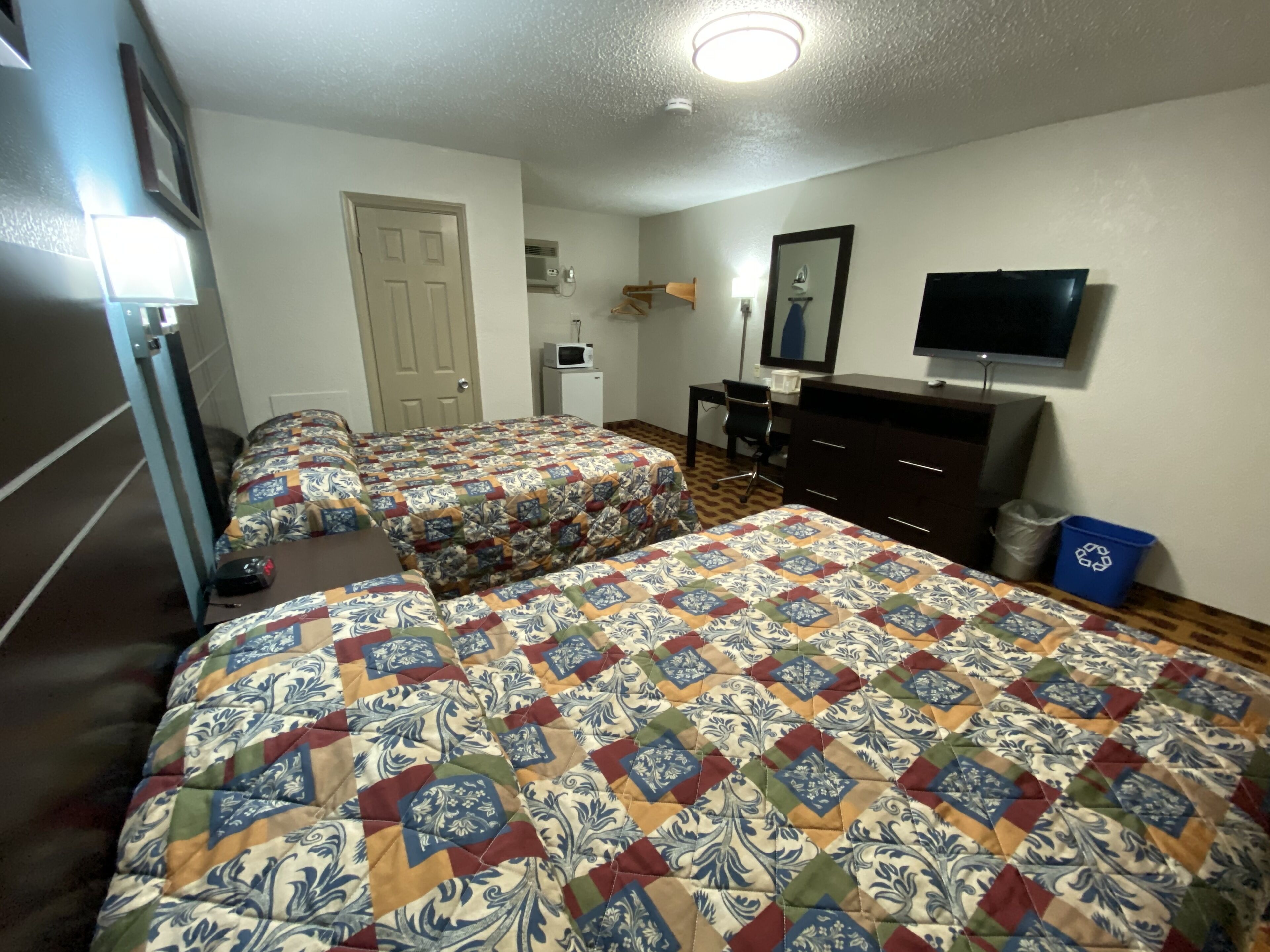 Een hotelkamer met twee bedden, een bureau, een televisie en een dressoir.