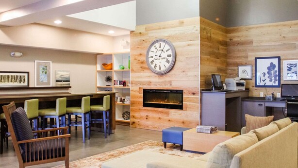 A modern living room with a fireplace, a dining area with chairs, and a kitchen area with a counter and appliances. - Country Inn & Suites by Radisson, Chester, VA (Chester)