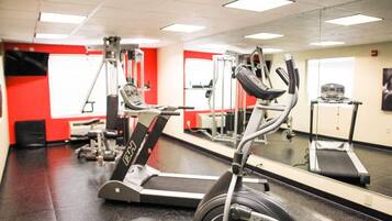 Un gimnasio con cintas de correr, elípticas y equipo de pesas.