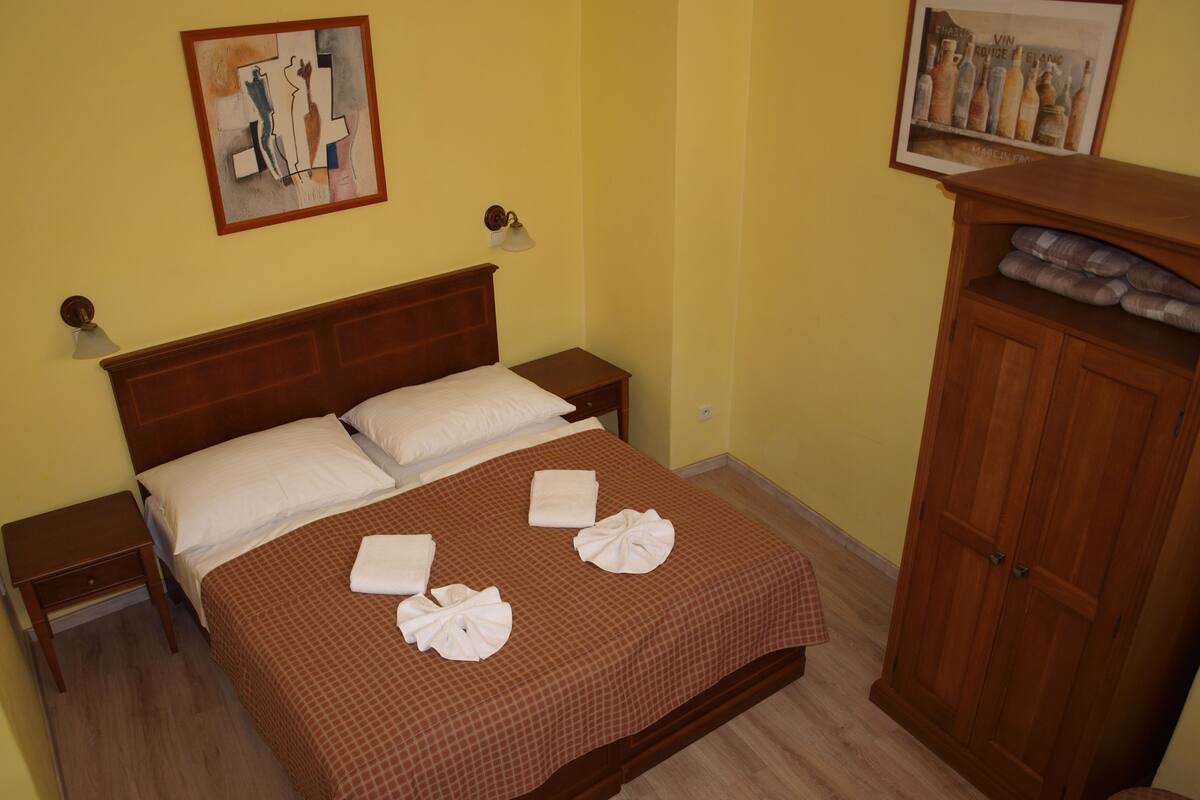 Una camera d'albergo con un letto in legno, due comodini, un armadio e opere d'arte alle pareti.