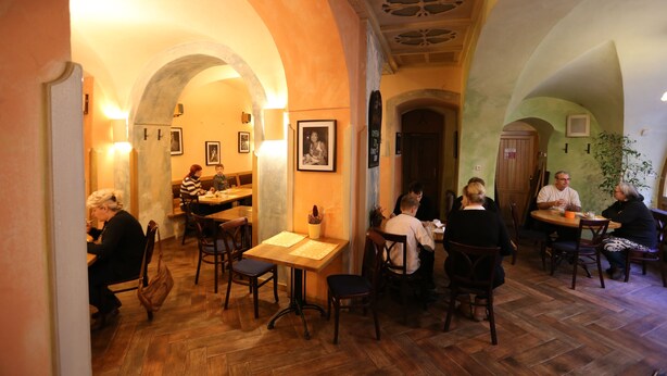 A restaurant with wooden floors and arched ceilings, featuring tables and chairs for dining. - Hotel King George (Prague)