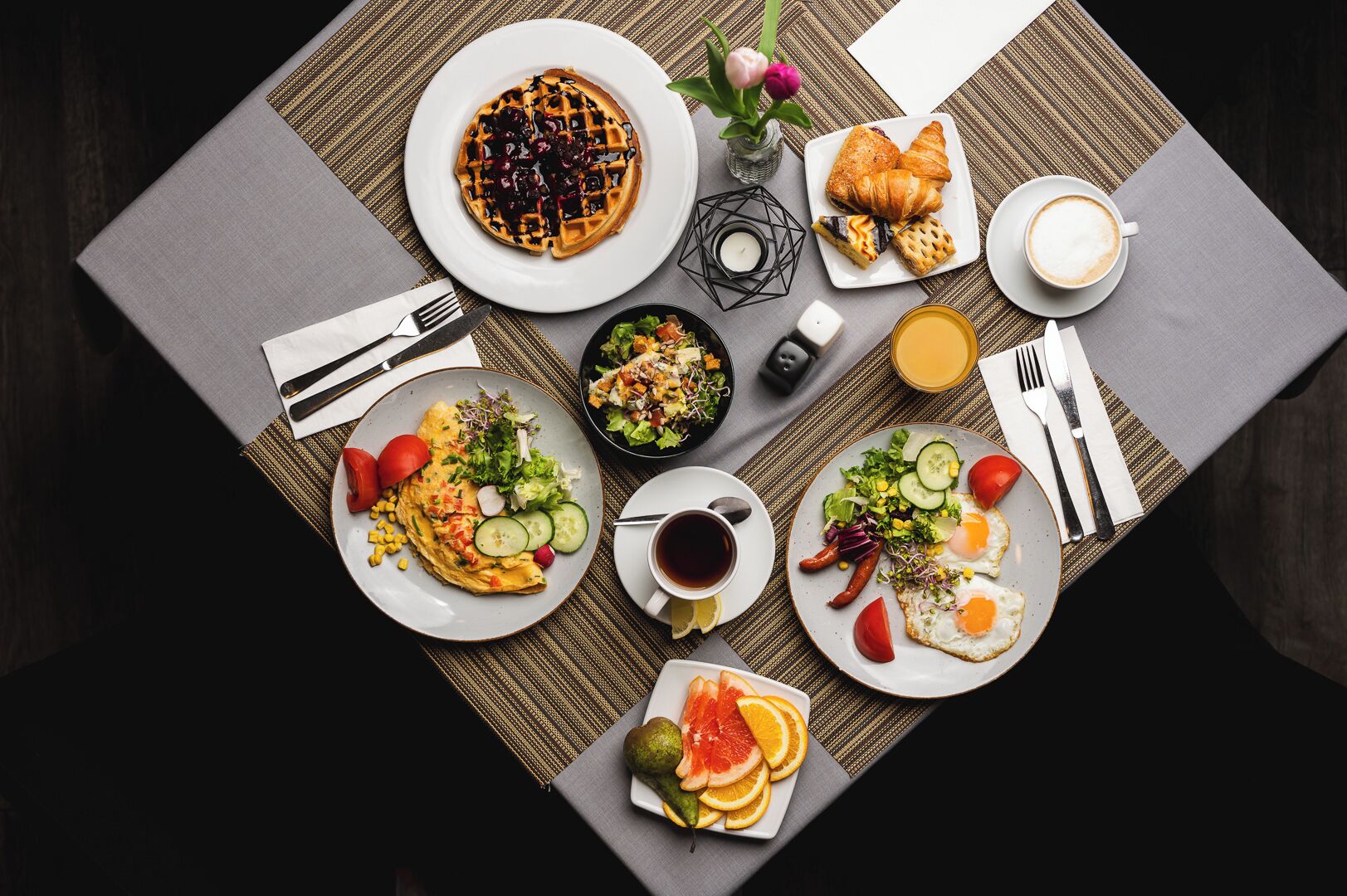 Ein Frühstücksbuffet mit verschiedenen Speisen, darunter Waffeln, Croissants, Eiern und Obst.