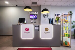 A reception desk with a clock, a television, and a sign that reads 'RECEPCJA'. - Hotel Focus Lodz (Lodz)