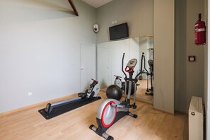 A gym with a stationary bike, elliptical, and exercise ball. - Hotel Focus Lodz (Lodz)