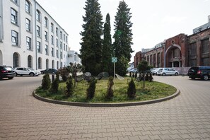 A paved roundabout with a central grassy area, surrounded by parked cars and buildings. - Hotel Focus Lodz (Lodz)