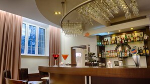 Un espace bar doté d’un comptoir incurvé, d’un porte-verres à vin et de diverses bouteilles exposées sur des étagères.