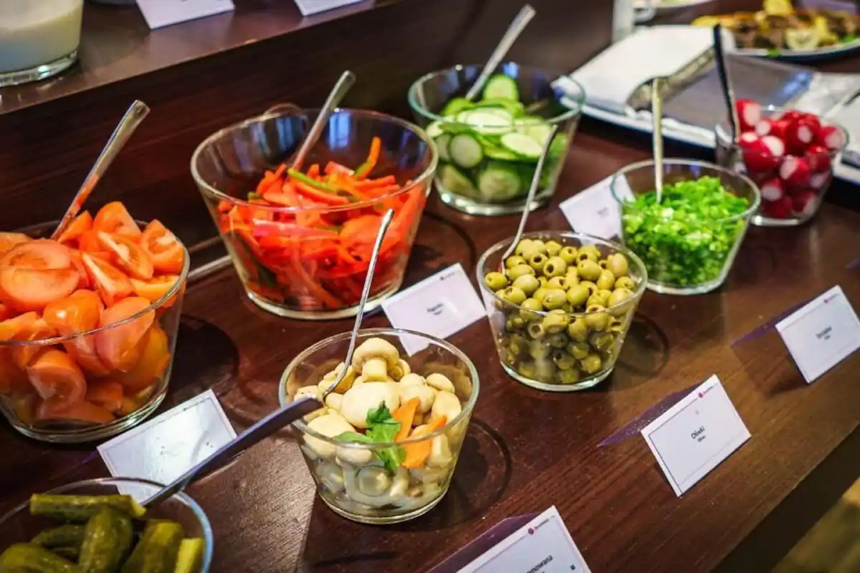 A buffet with various food options including carrots, cucumbers, olives, and pickles.