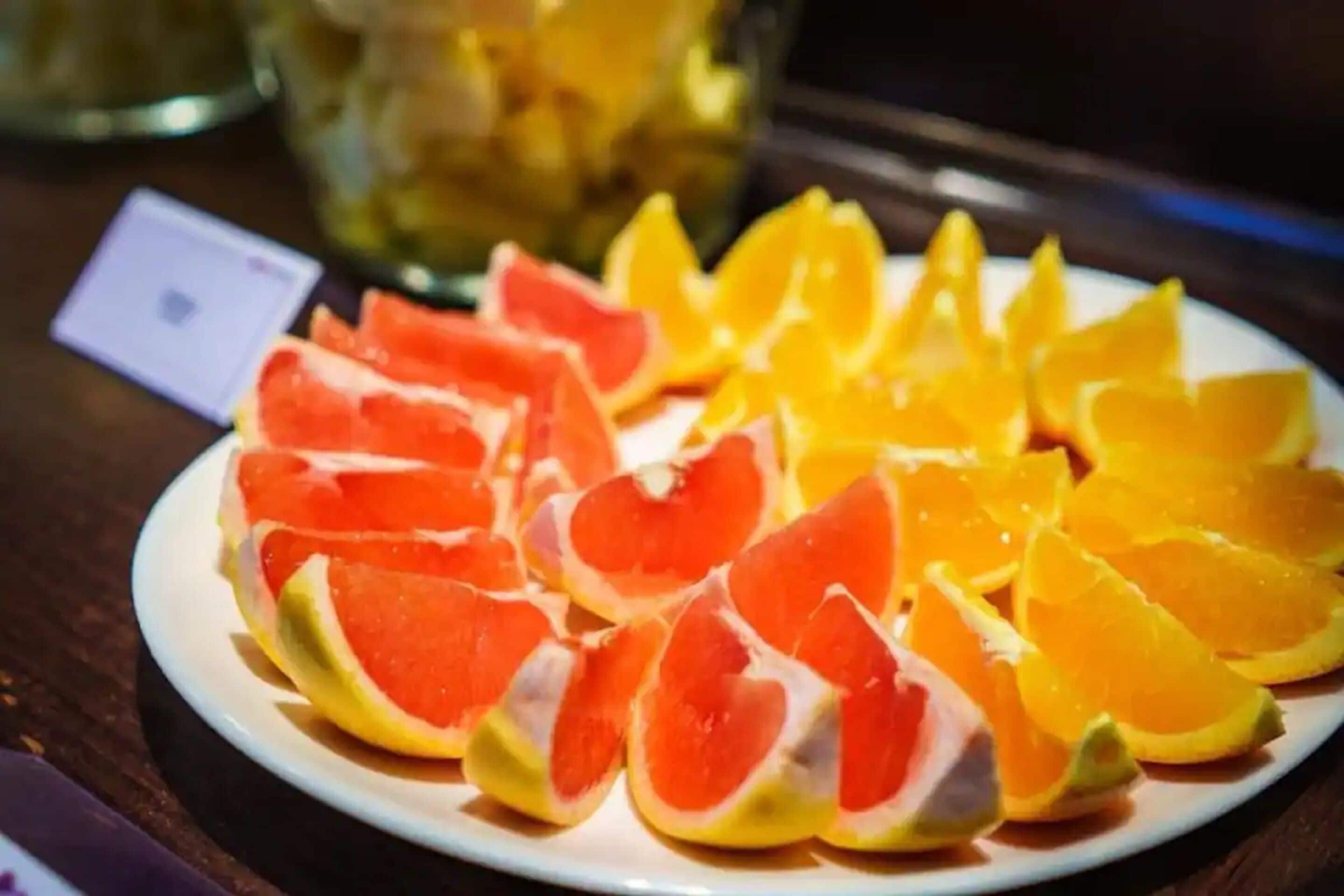 Un plato con frutas cortadas, como pomelo y naranja, sobre una mesa.