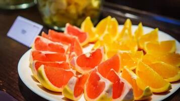 En tallrik med skivade frukter, inklusive grapefrukt och apelsiner, står på ett bord.