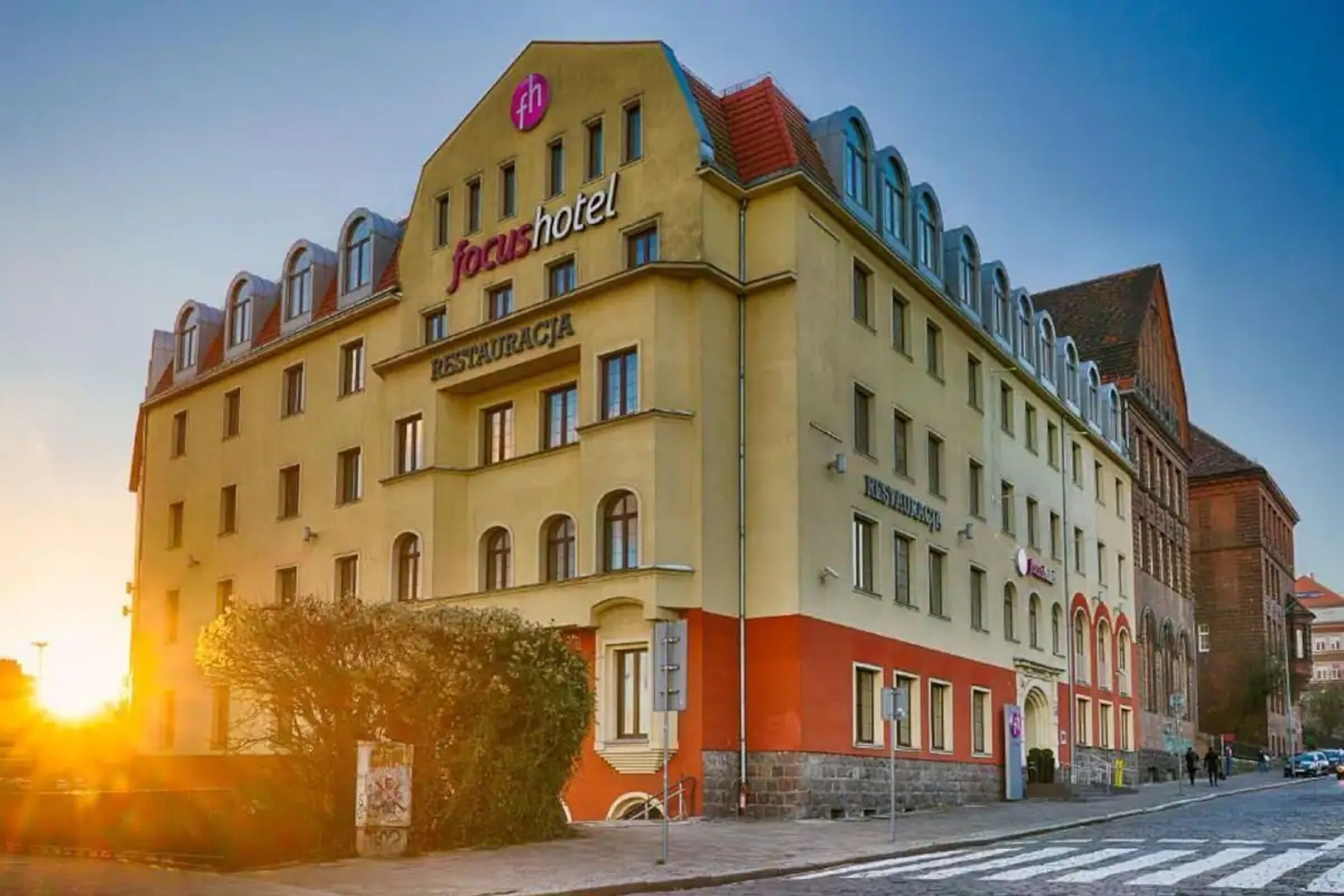 Un hotel con fachada amarilla, varias ventanas y un cartel que dice "focushotel".