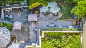 An aerial view of a rooftop patio with outdoor seating, umbrellas, and a person sitting. - Corvin Hotel Budapest - Corvin wing (Budapest)