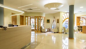 A modern hotel lobby with a reception desk, seating area, and large windows. - Corvin Hotel Budapest - Corvin wing (Budapest)