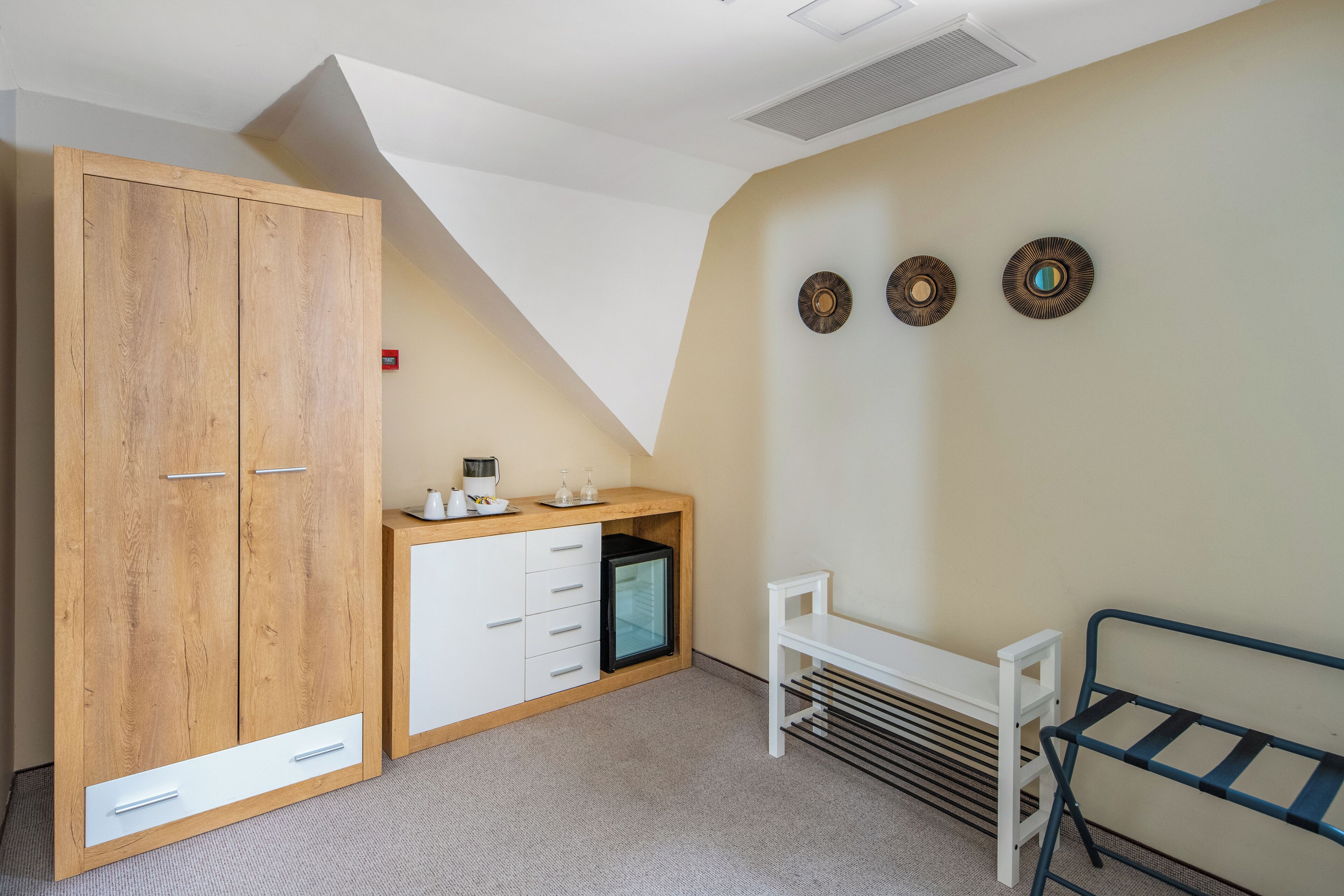 A bedroom with a wooden wardrobe, a small desk, and a bed.