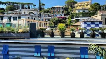 A coastal hotel with balconies, a checkered facade, and a view of historic buildings and trees.