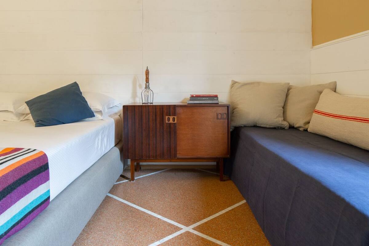Een kleine, knusse kamer met een bed, een slaapbank en een houten kast.
