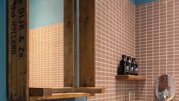 Un baño con tocador de madera, pared con azulejos y zona de ducha.