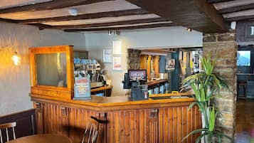 Angolo bar con un bancone in legno, uno schermo televisivo e un cartello pubblicitario di Cask Ales.