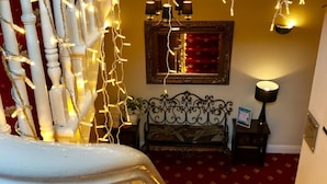A staircase with white balusters and string lights, leading to a room with a red carpet and a decorative mirror. - Old Rose and Crown Hotel (Birmingham)