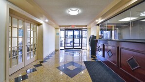 Un vestíbulo de hotel con mostrador de recepción y puerta de acceso al estacionamiento.