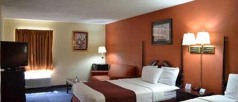 Habitación de hotel con dos camas, televisión, escritorio y ventana con cortinas.