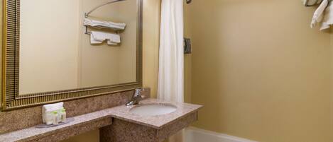 A bathroom with a sink, mirror, and bathtub.