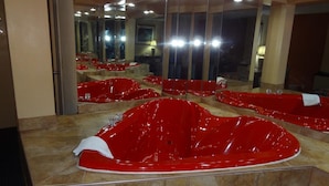 Habitación con varios bañeras rojas y un espejo grande que refleja el ambiente.