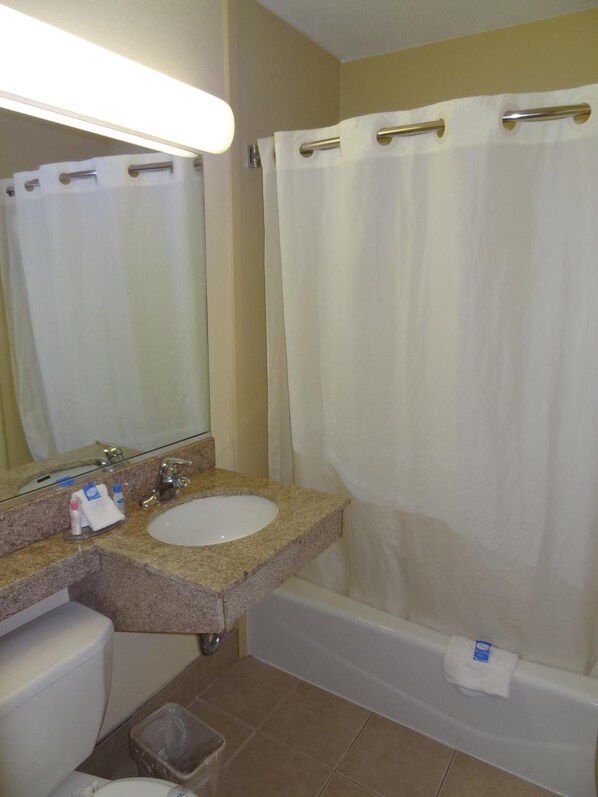 A bathroom with a sink, mirror, toilet, and bathtub.