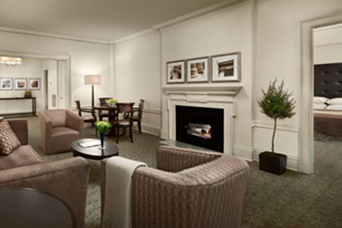 A hotel room with a fireplace, a dining area, and a seating area with chairs and a small table.