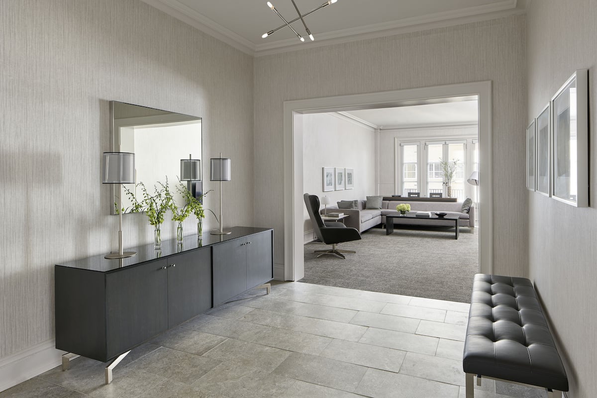A modern living room with a dark grey console, a large mirror, and a contemporary light fixture.