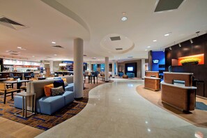 Un vestíbulo de hotel moderno con un mostrador de recepción curvo, zonas de estar y un bar.