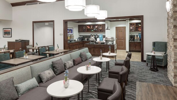 A hotel lobby with a seating area, a coffee station, and a kitchen visible through an open doorway. - Homewood Suites by Hilton El Paso Airport (El Paso)
