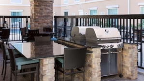 An outdoor patio with a stone grill, dining table, and chairs. - Homewood Suites by Hilton El Paso Airport (El Paso)