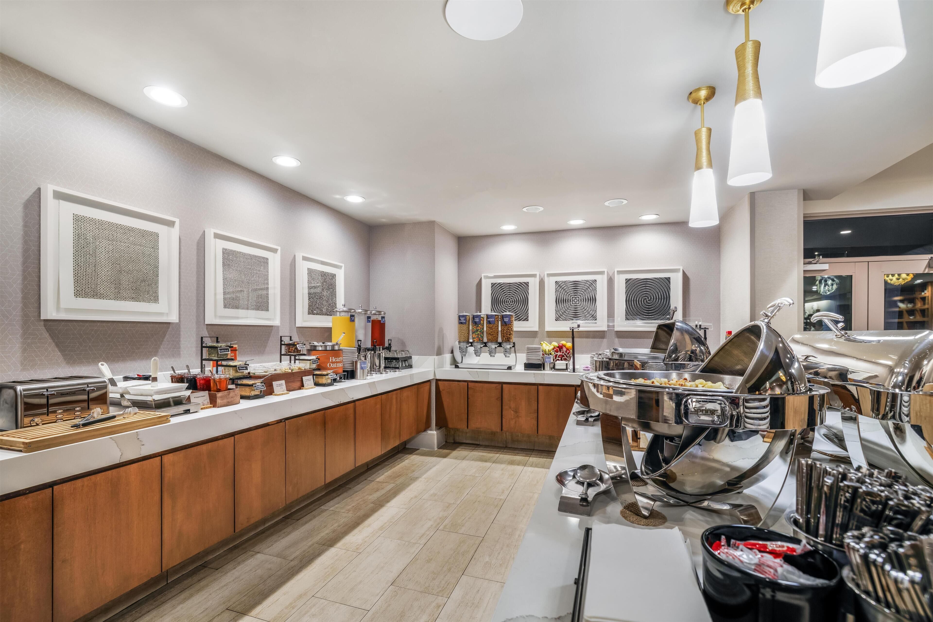 A modern kitchen with a long counter, equipped with various appliances and utensils, and a central island with a sink.
