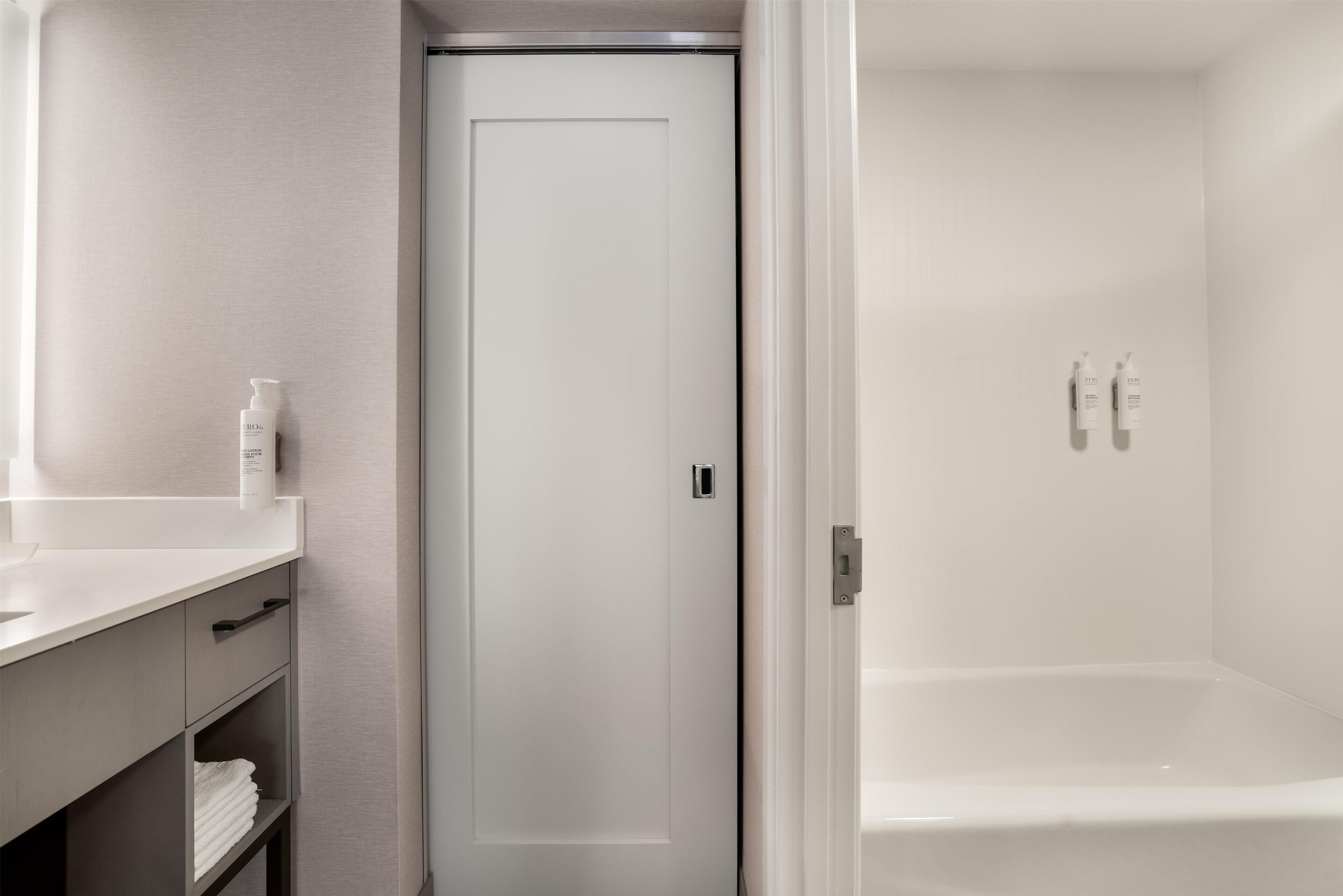 A bathroom with a white sink, mirror, and toiletries.