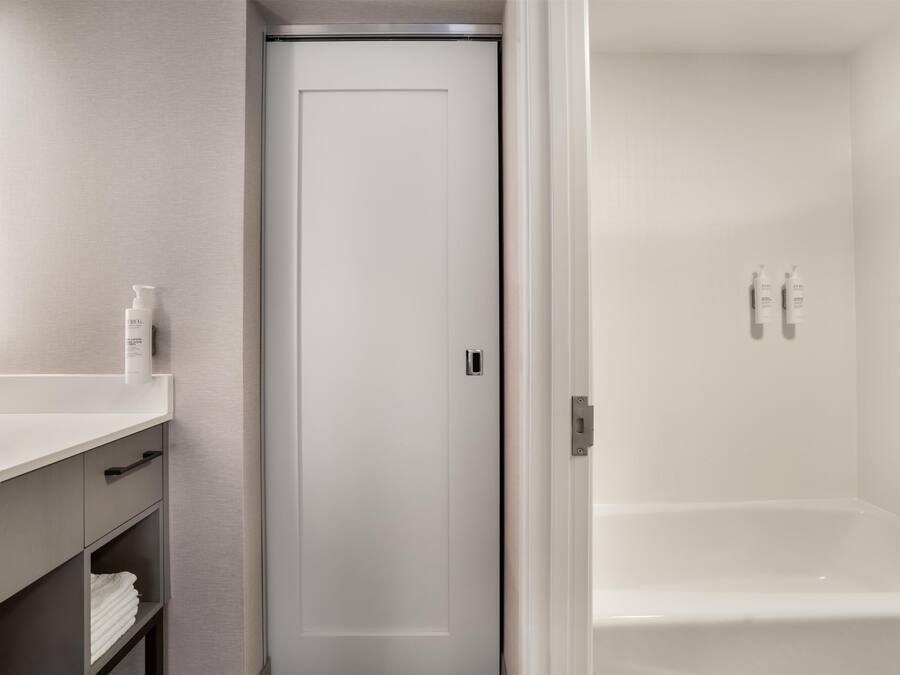 A bathroom with a white sink, mirror, and toiletries.