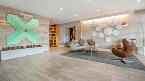 A modern living room with a large abstract wall art, a sofa, a coffee table, and a unique chair. - Homewood Suites by Hilton Dallas-Frisco (Frisco)