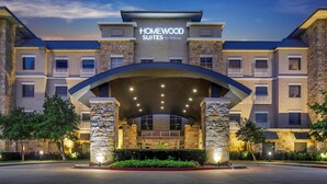 A hotel entrance with a stone facade, multiple balconies, and a clear sky. - Homewood Suites by Hilton Dallas-Frisco (Frisco)