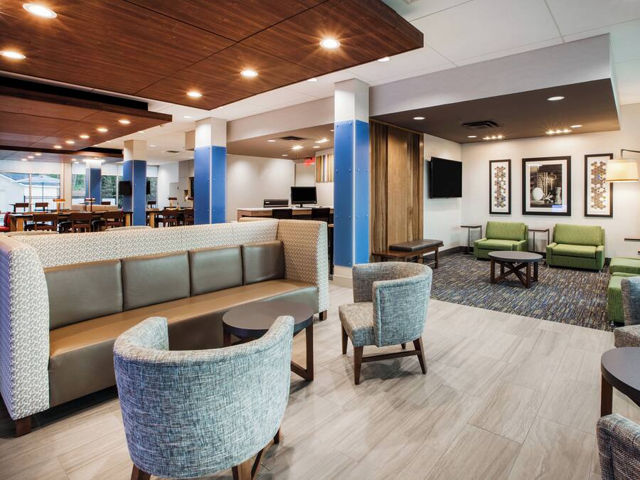 A hotel lobby with seating areas, a reception desk, and a television.