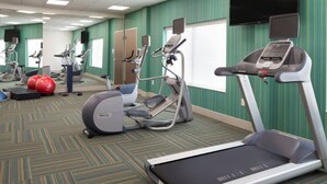 Un gimnasio con cintas de correr, elípticas y pelotas de ejercicio.
