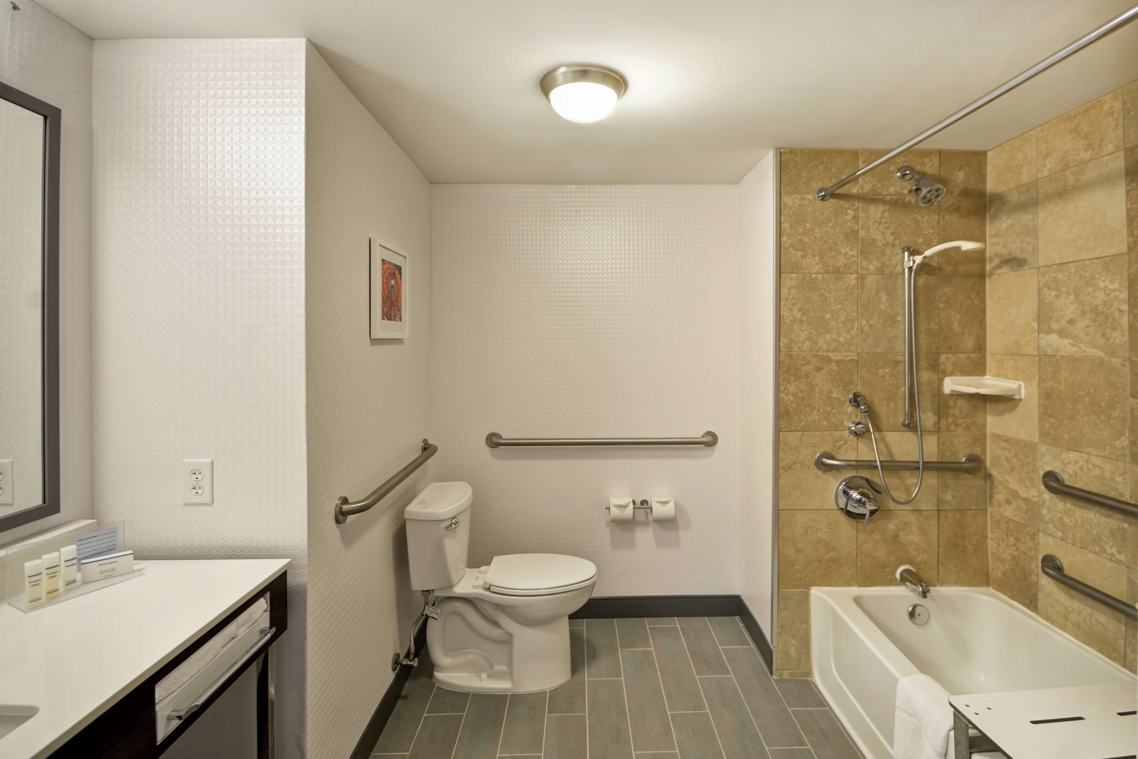 A bathroom with a toilet, sink, and bathtub. It includes grab bars and a shower area.