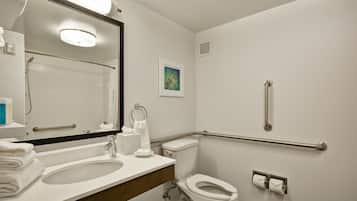 Un baño con lavamanos, inodoro y barras de apoyo.