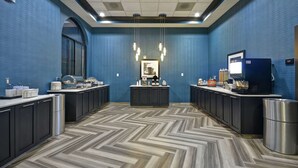 Een moderne hotel lobby met een lange receptiebalie, een koffiehoek en een groot raam.