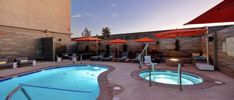 A swimming pool area with lounge chairs and umbrellas.