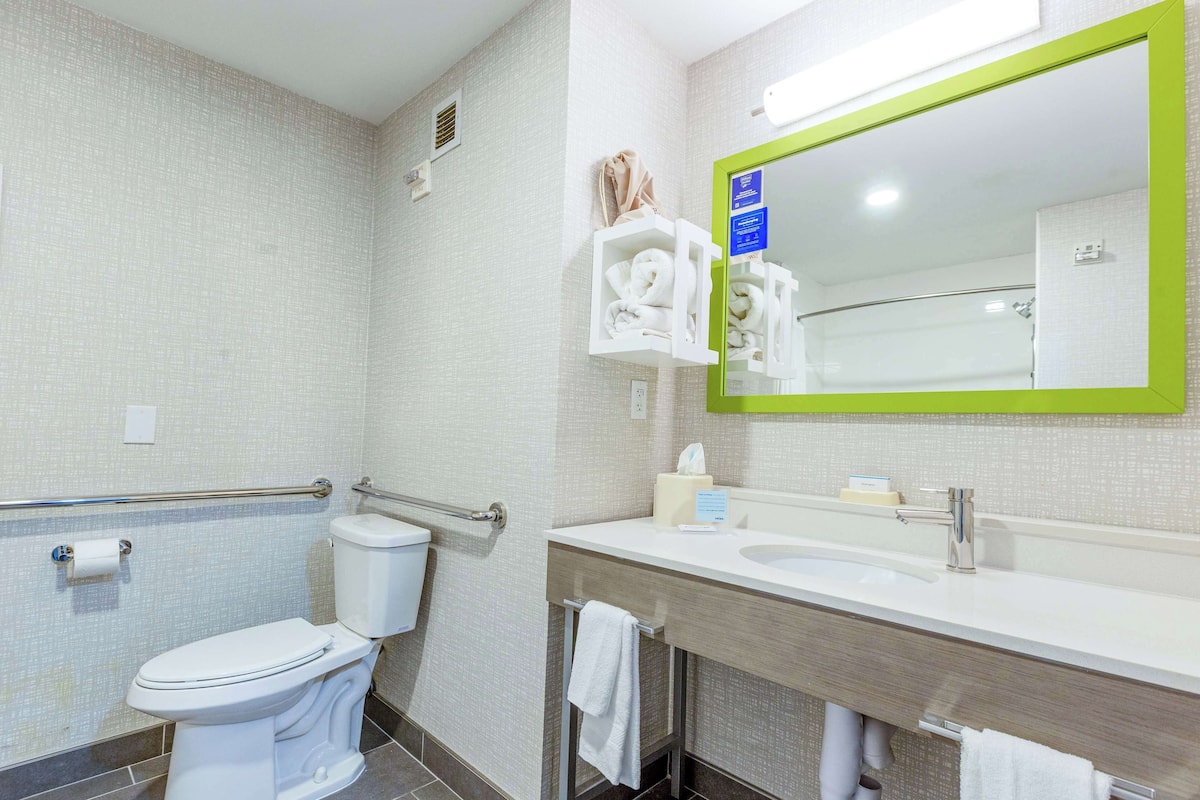 A modern bathroom with a toilet, sink, and mirror.