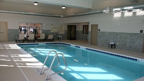 Une piscine intérieure avec des lignes de démarcation claires pour chaque couloir, un panneau indiquant qu’il est interdit de plonger et un poste de surveillance pour le sauveteur.