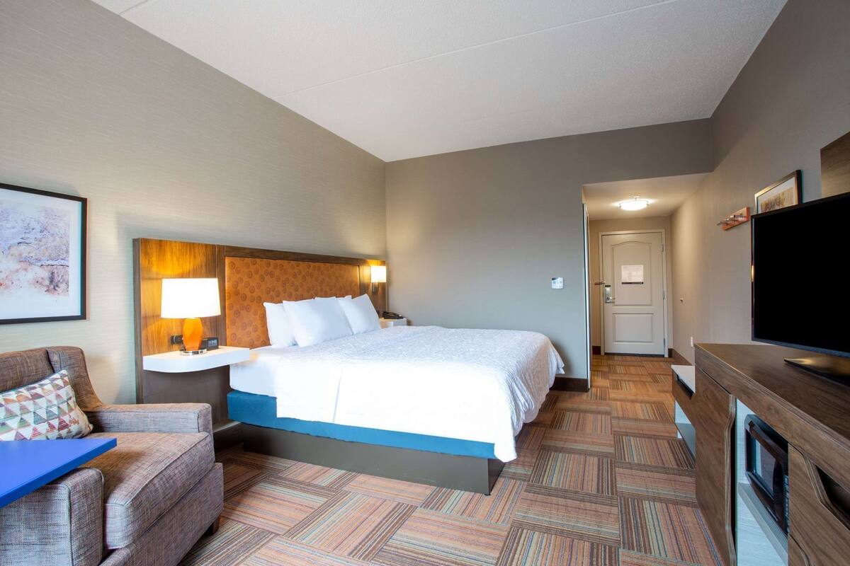 Ein Hotelzimmer mit Bett, Schreibtisch, Fernseher und einer Couch.